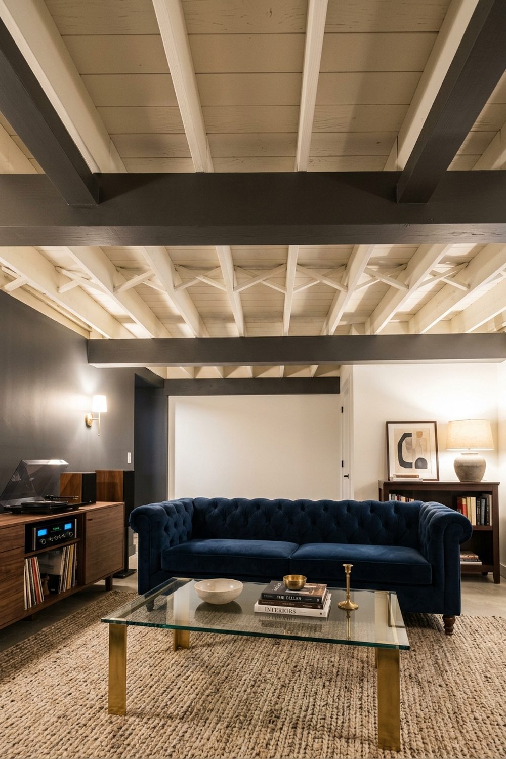 Two Tone Painted Joist and Beam Ceiling Basement with two tone painted ceiling showing charcoal beams and white joist bays above a navy velvet sofa