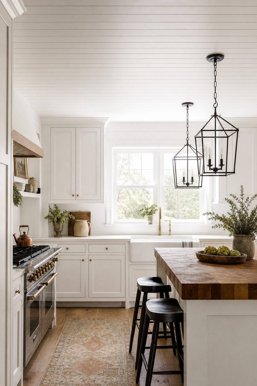 Crisp white shiplap ceiling in a farmhouse kitchen with exposed black metal lantern pendants, white shaker cabinets, and a butcher block island