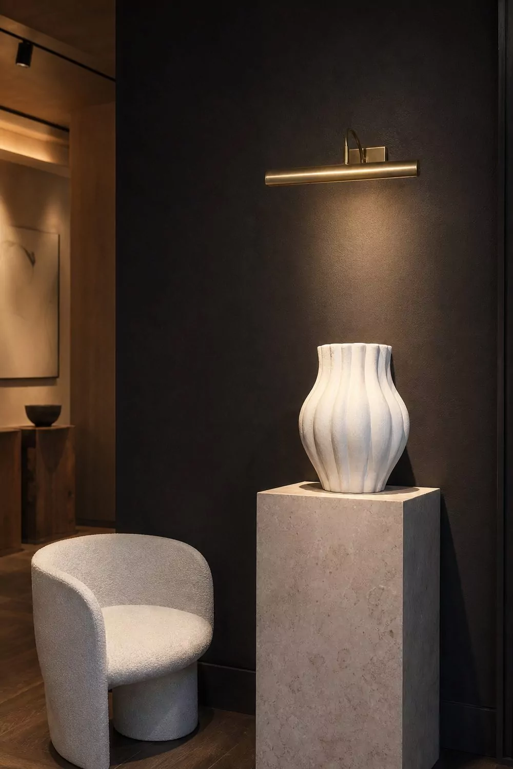 Showroom with a dramatic deep charcoal accent wall behind a light reflective product, crisp accent lighting creating strong gallery contrast