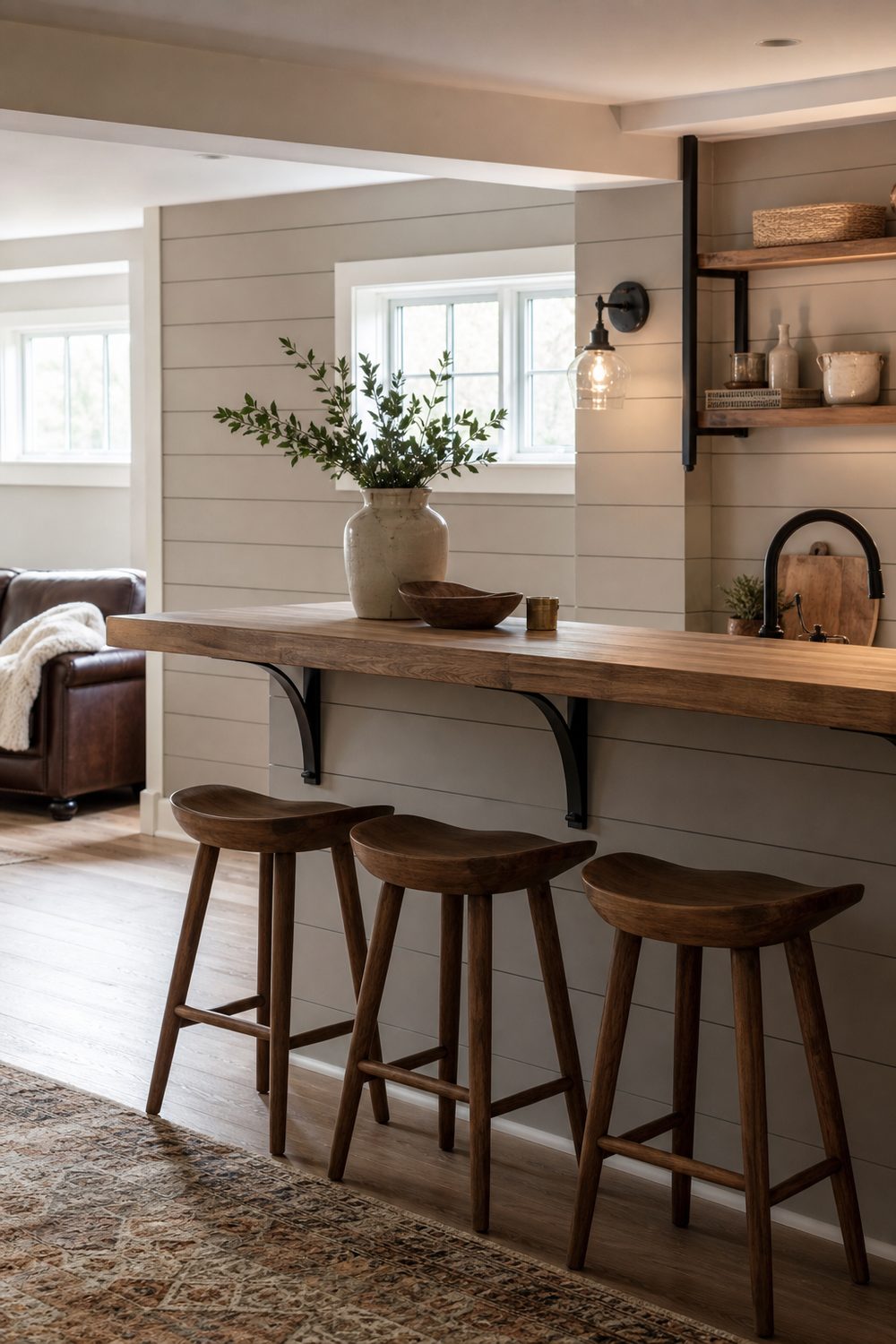 Farmhouse basement bar with painted greige shiplap wall, a simple wood counter and black iron hardware