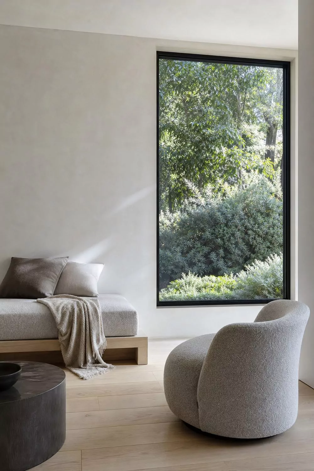 Modern minimalist she shed with clean white walls, a low platform daybed, a sculptural chair, and one large picture window