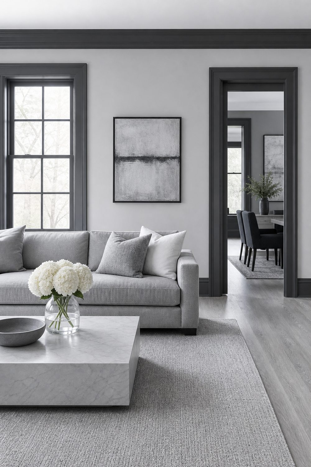 Light grey living room walls with charcoal grey window casings, door trim and baseboards above a grey sofa