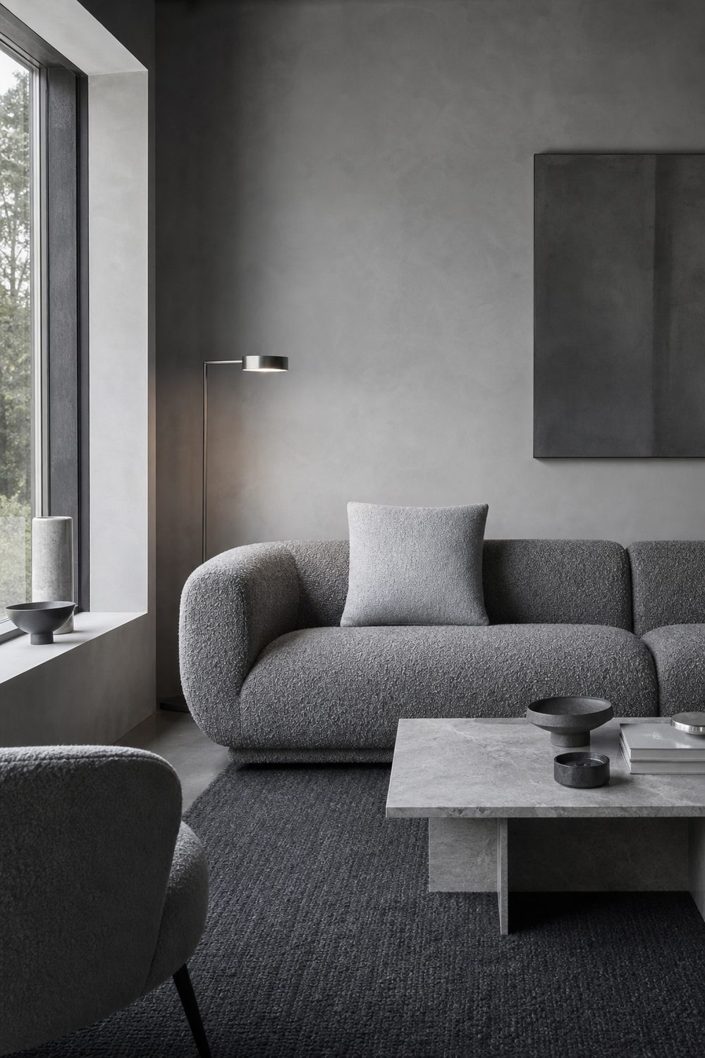 Monochrome grey minimalist living room with boucle sofa, dove plaster walls, charcoal wool rug and brushed steel