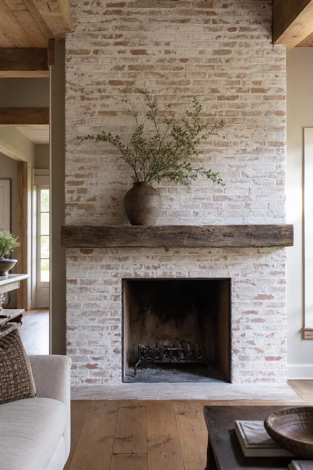 Floor to ceiling whitewashed brick fireplace with warm red brick showing through thin limewash in a farmhouse living room