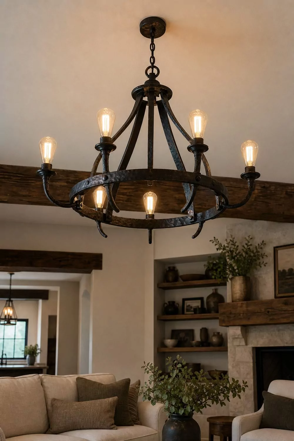 Black wrought iron chandelier with six exposed warm filament bulbs hanging above a farmhouse living room