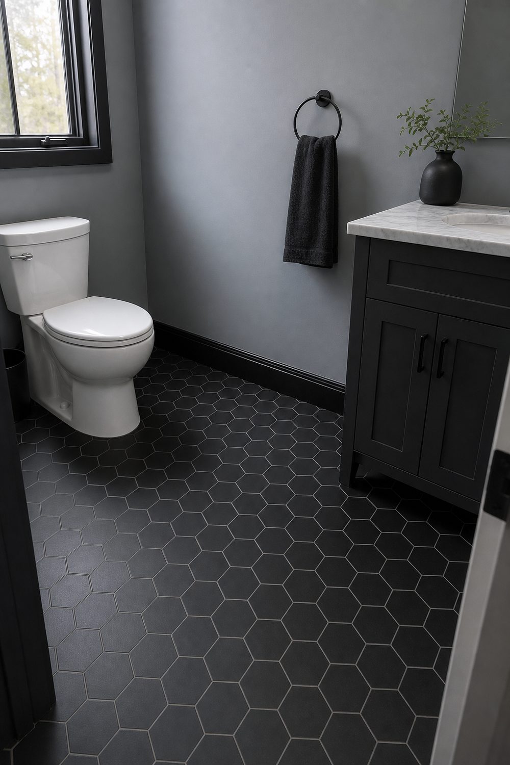 Small black hexagon floor tile with pale grey grout in a bathroom with soft grey painted walls and a white pedestal sink