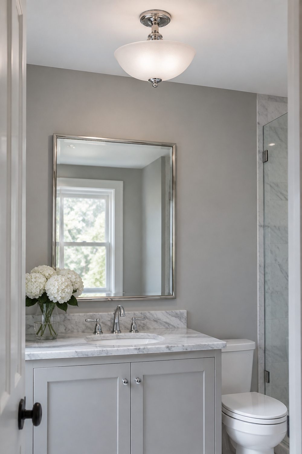 Frosted glass semi flush mount ceiling fixture on a short chrome stem above a marble vanity in a soft gray guest bathroom